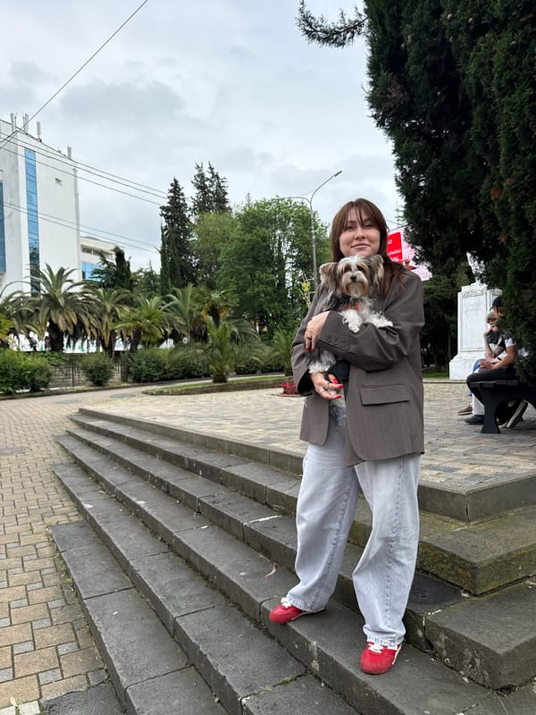 Woman walks small dog on Sochi sidewalk