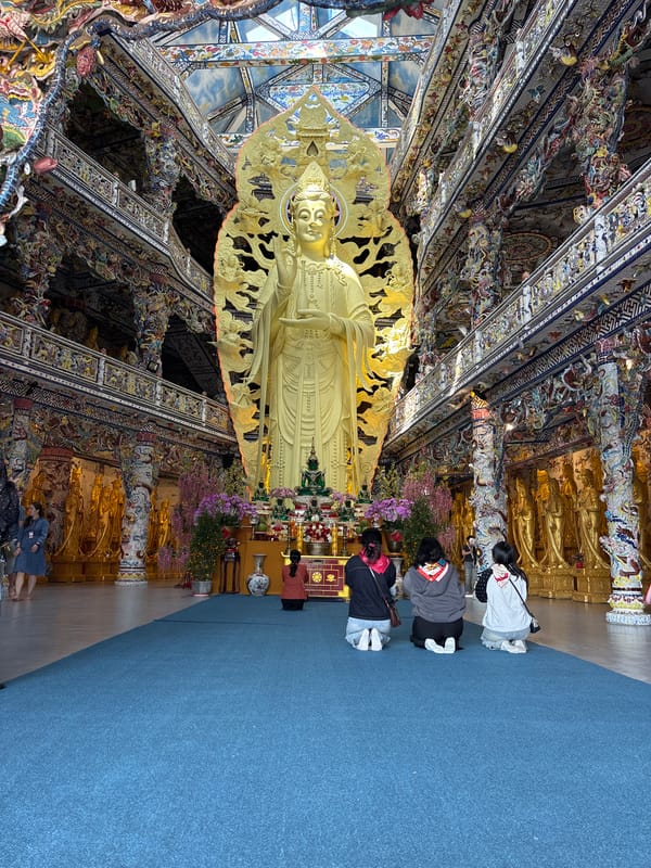 Worshippers pray at gold Buddha statue in Vietnamese temple