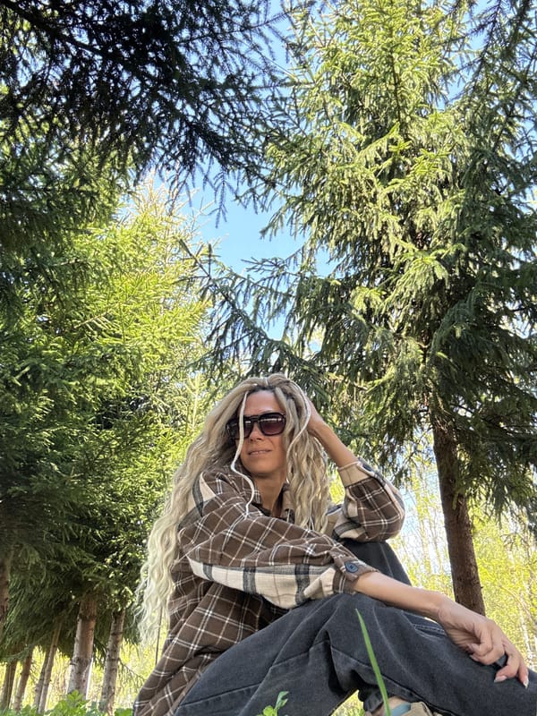 Woman in plaid photographed among trees from ground level