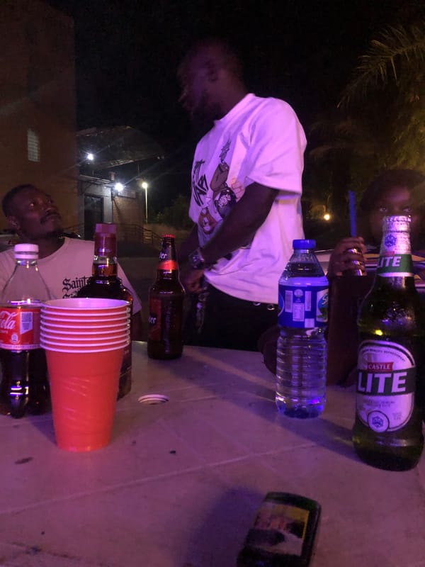Friends gather for nighttime drinks outdoors under colored lights