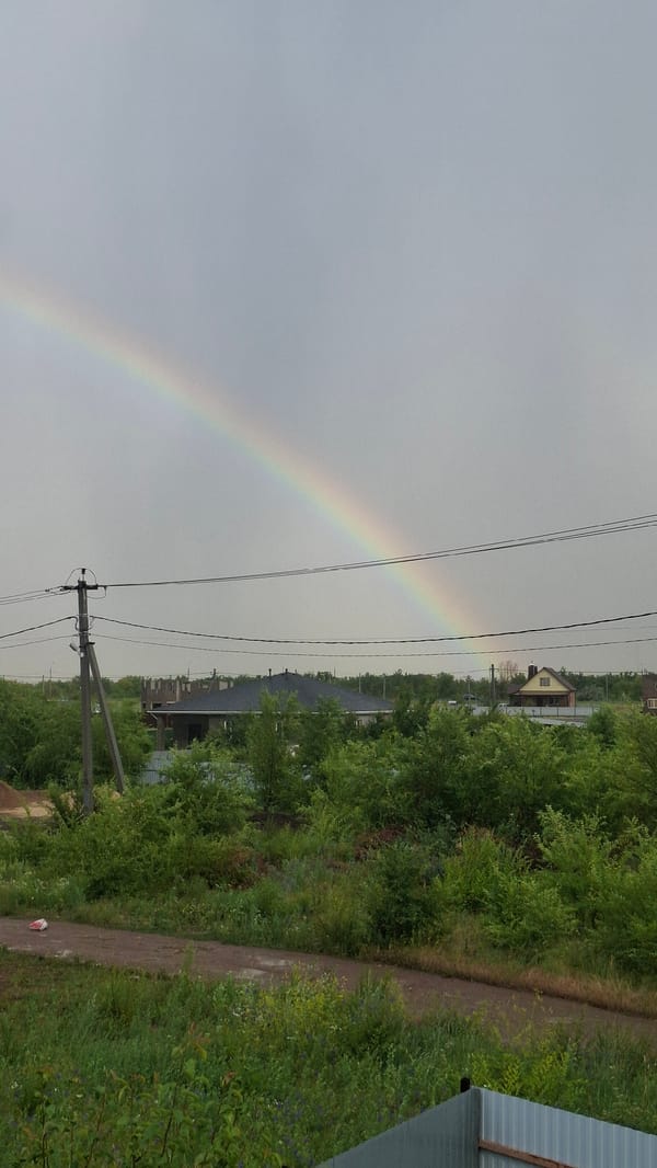 Rainbow over rural Engels under a cloudy summer sky