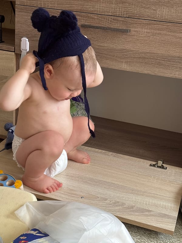 Toddler explores furniture while selfies are taken nearby