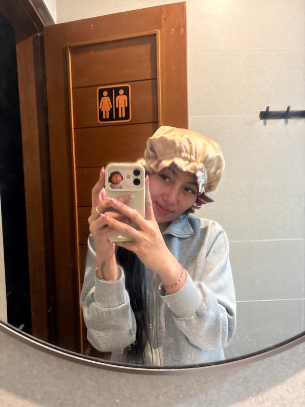Person takes mirror selfie wearing bonnet and casual attire