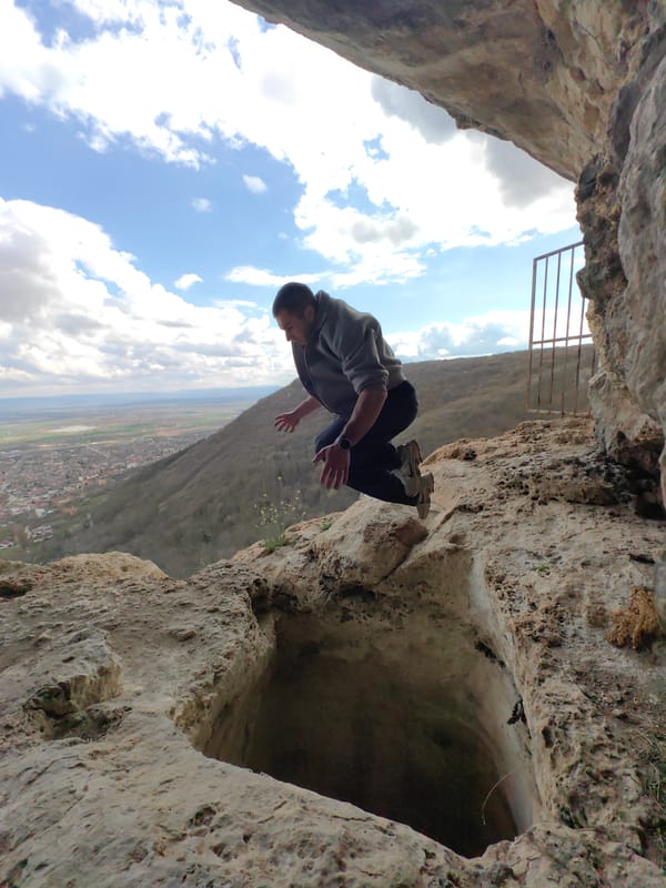 Man jumps over circular hole in rocky terrain, Shumen