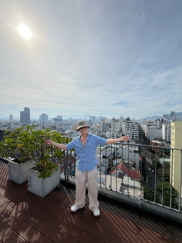 Man photographed on rooftop balcony overlooking Đà Nẵng cityscape