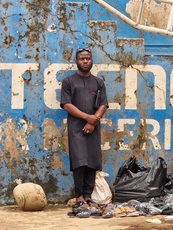 Street life near a Technicolor Nigeria storefront on a busy urban day