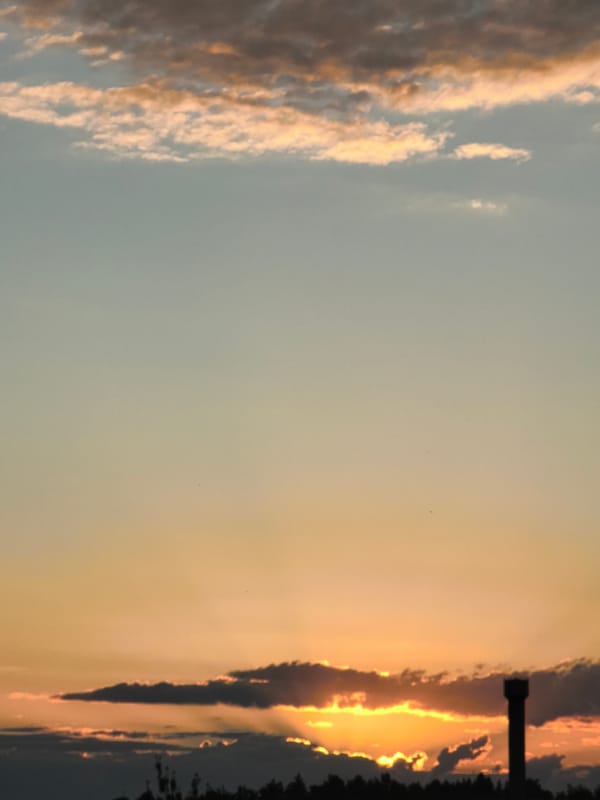 Water tower silhouetted against a vivid urban sunset