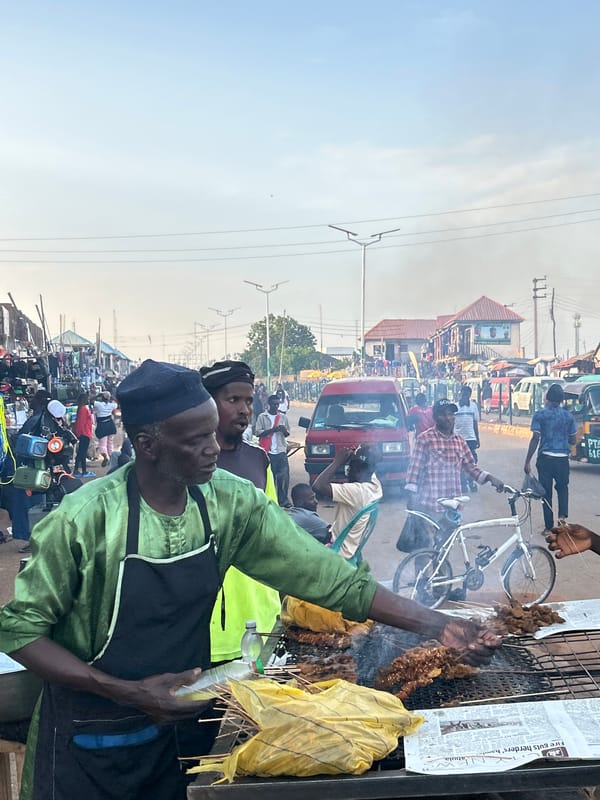 Street food vendors serve customers in Jos marketplace