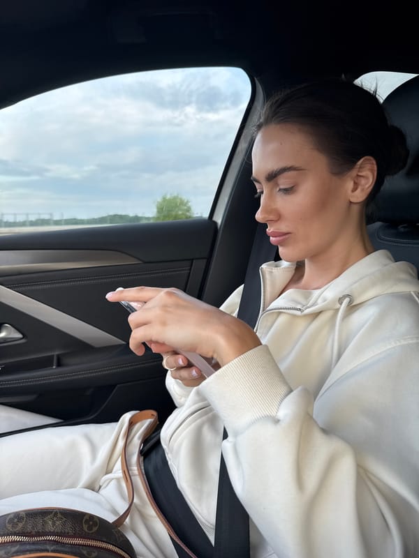 Woman in white hoodie sleeps, poses in car