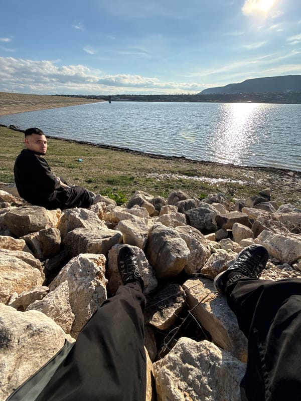 Person sits by water on rocky embankment in Shumen