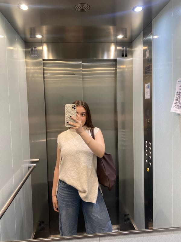 Woman takes mirror selfie in metal elevator