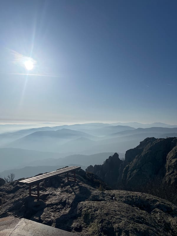 Person sits atop Bulgarian mountain peak overlooking misty valley
