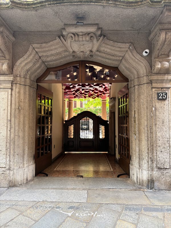 Stone building entrance with ornate archway documented in Milan