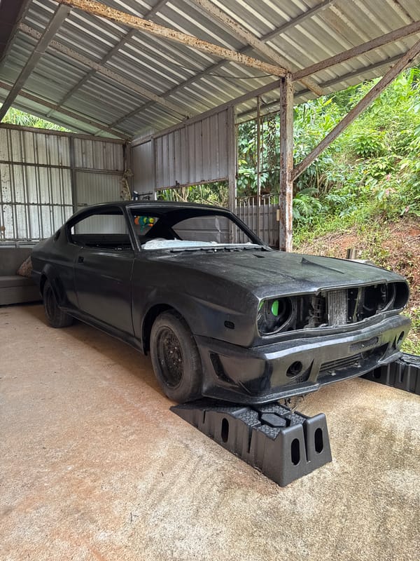 Bare-front black car up on ramps mid-restoration in Karon