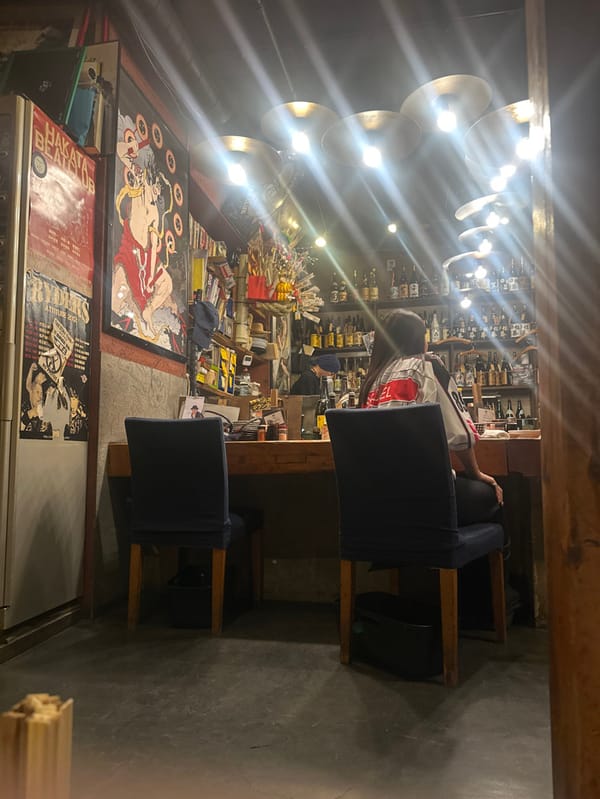 Customer sits at wooden bar counter in Shibuya izakaya