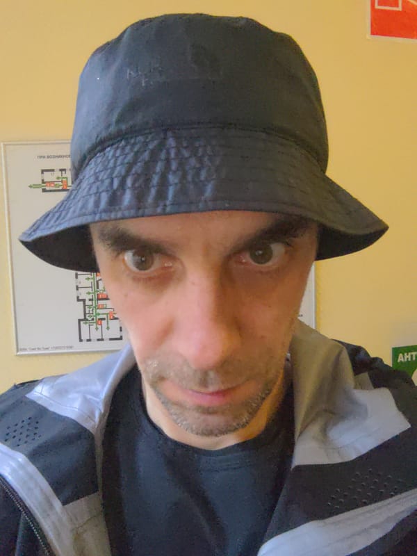 Man in bucket hat poses for selfie near schematic diagram