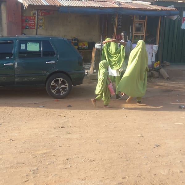Two pedestrians in lime green walk past car in Dadi Riba
