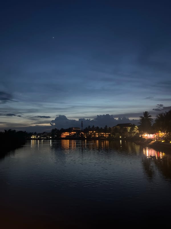 Hoi An riverfront at dusk: bridges, palms, and waterside lights
