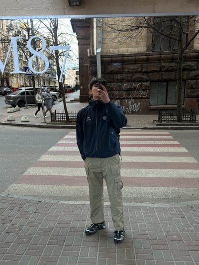 Person photographs storefront reflection on Kyiv street