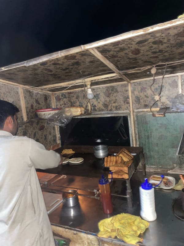 Food vendor serves customers at nighttime stall in Karamsar
