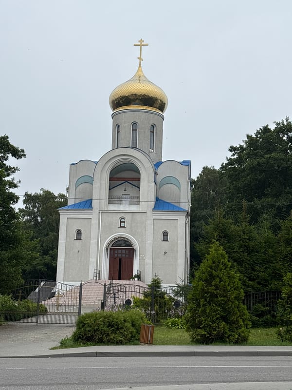 Orthodox church and a red Dodge Challenger in Pionersky, Russia