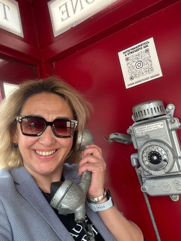 Woman uses vintage rotary phone in red booth, Kazakhstan
