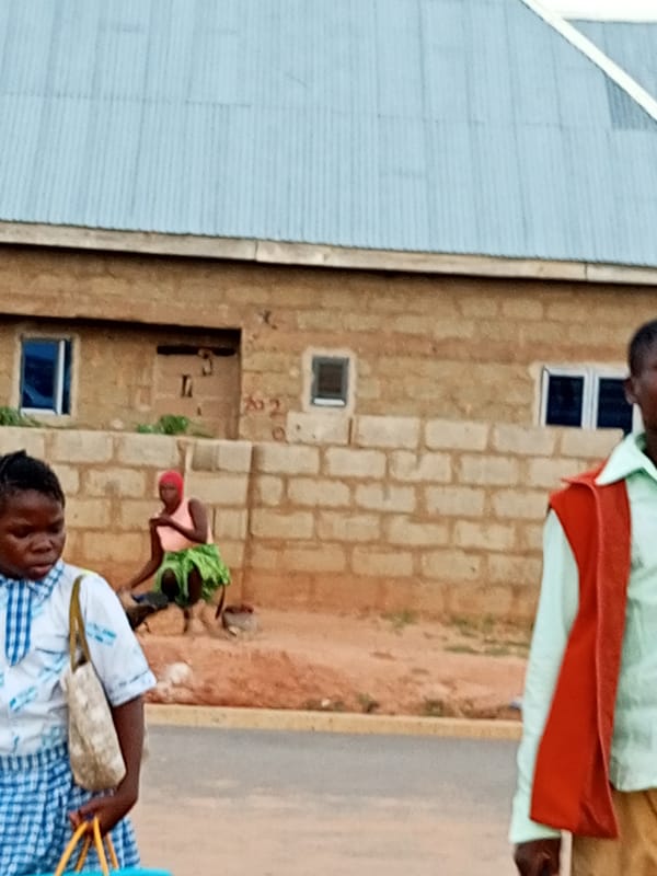 Everyday street life around a brick building in Gombe, Nigeria