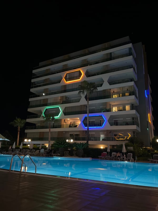 Alanya resort at night — pools, lit facades, and old stone steps