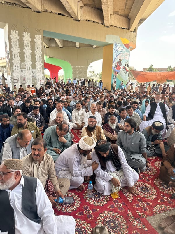 Large traditional outdoor gathering under overpass in Quetta