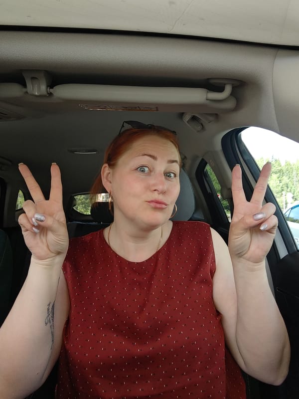 Woman makes peace signs while posing in car in Chaikovsky