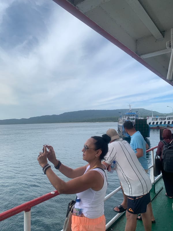 Ferry passengers photographing and moving about vessel near Melaya, Indonesia