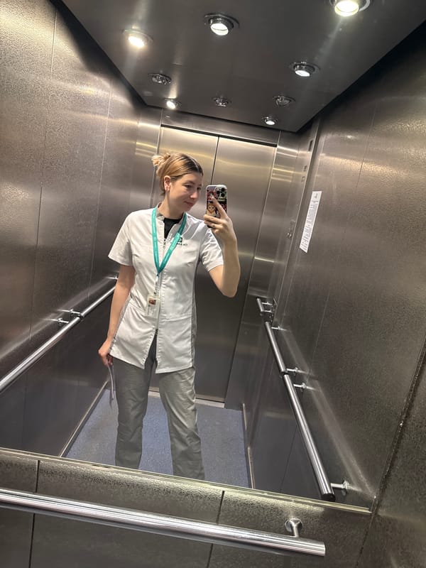 Lab coat-wearing person takes elevator selfie early morning