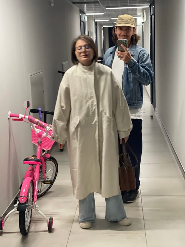 Two people observed in tiled hallway with pink bicycle