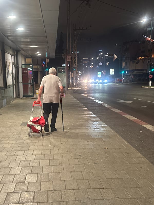 Elderly man shops along illuminated Israeli streets at night