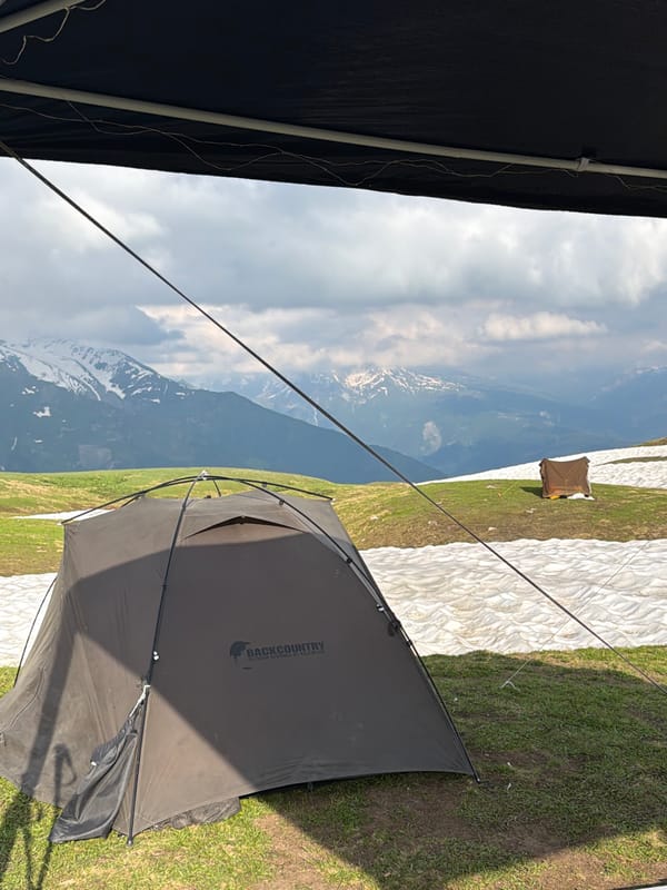 Backcountry camp in Mestia with skewers, snow, and mountain skies