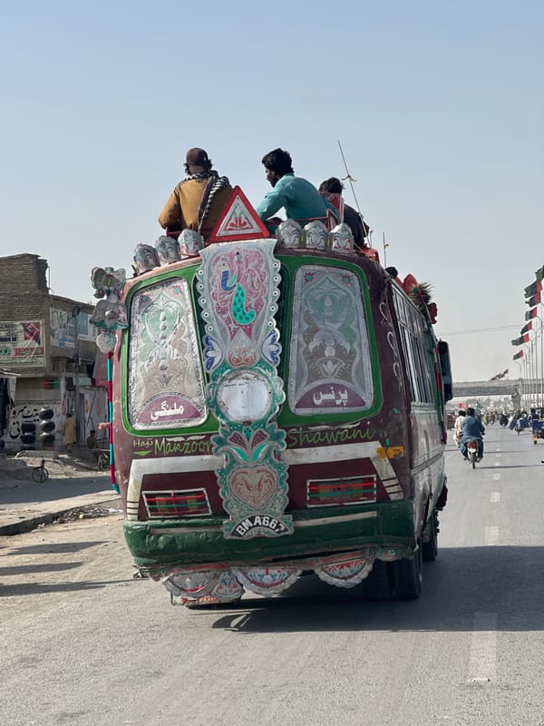 Decorated bus with roof passengers travels through Quetta