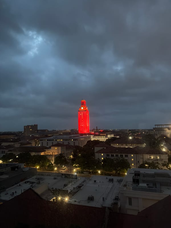 UT Tower glows red in Austin nighttime aerial view