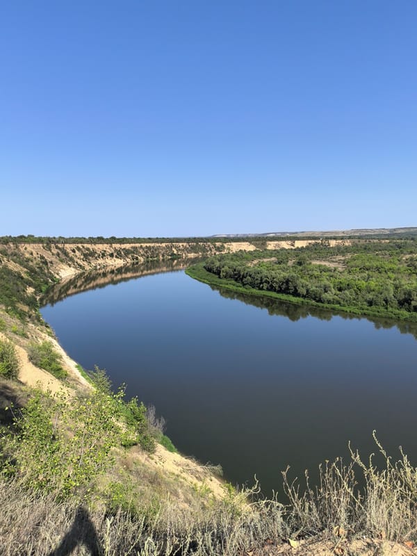 Wide river valley seen from above, calm and sun-lit