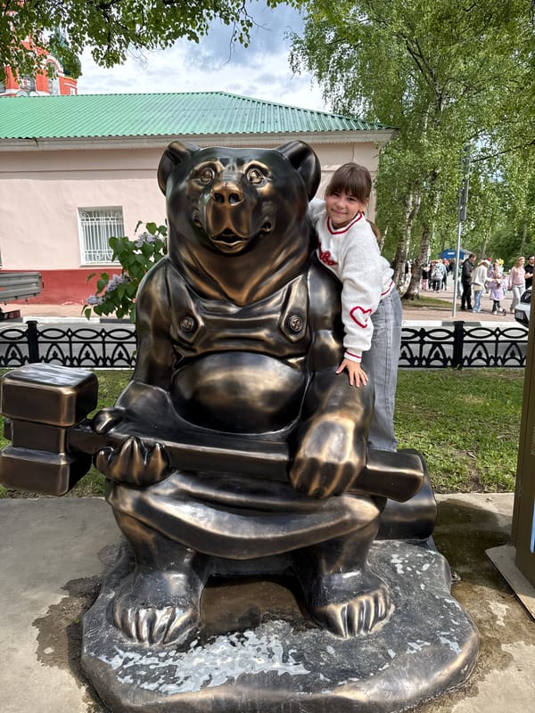 Visitors pose with bronze bear statue in Rusanovo