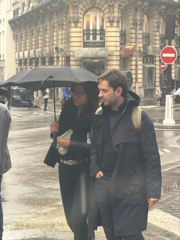 Parisians navigate afternoon rainstorm with umbrellas near city center