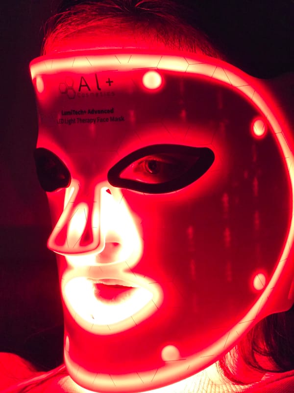 Person Uses Red LED Light Therapy Mask in Dark Room