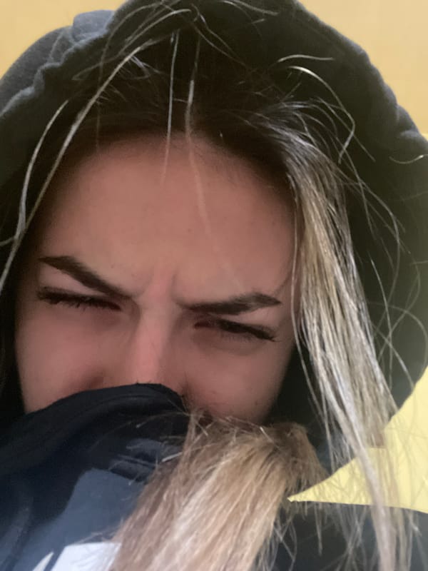 Person in black hoodie photographed with eyes closed in Kavarna