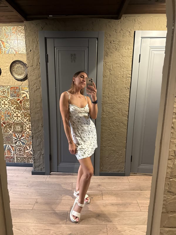 Mirror selfies in a Kazan restroom, white floral dress