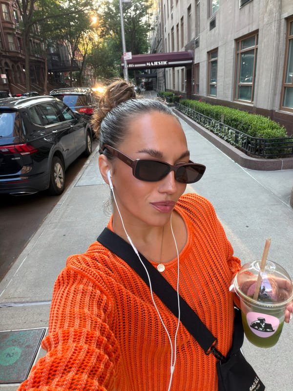 Sunny sidewalk selfie in a bold orange sweater, NYC