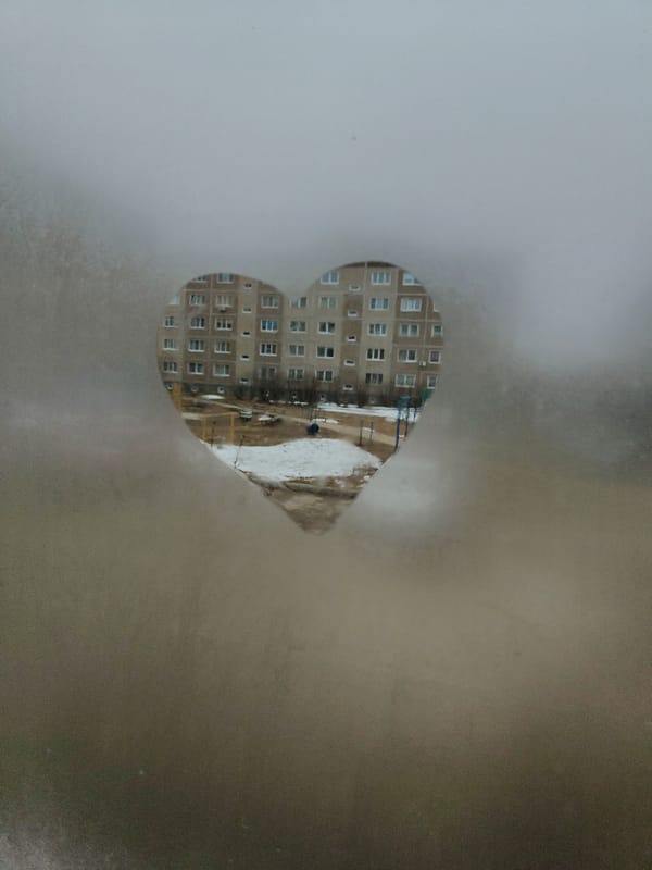 Heart traced in window condensation frames apartment building view