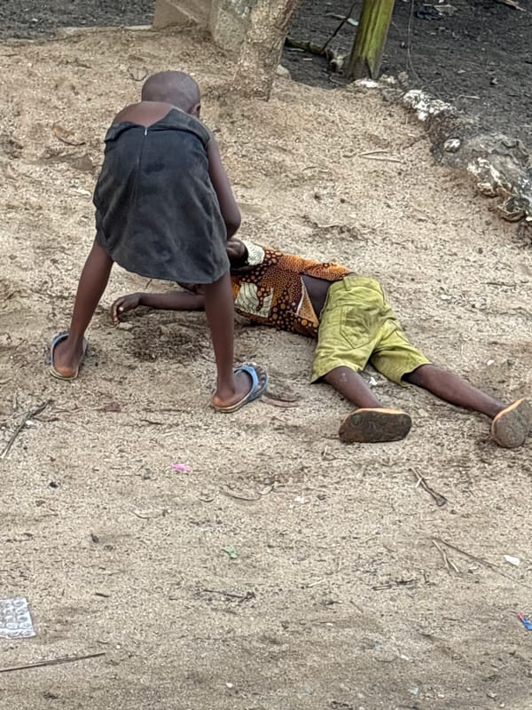 Children rest, person holds dog in Ikot Ekpene afternoon