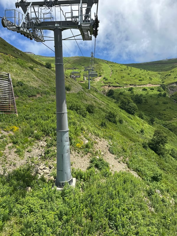 Riding a ski lift up a lush green mountain in summer