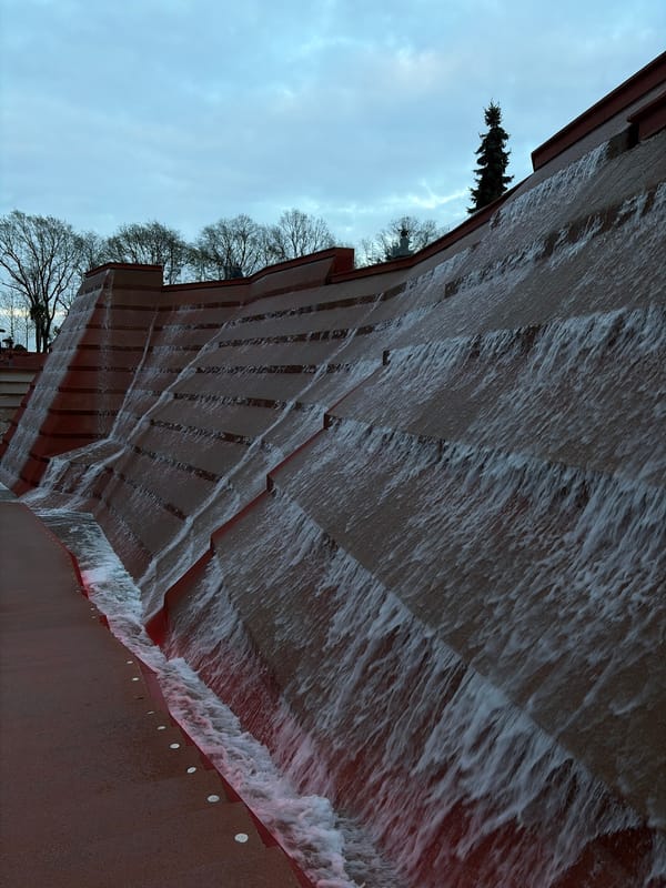 Person documents tiered waterfall feature and portraits at public space