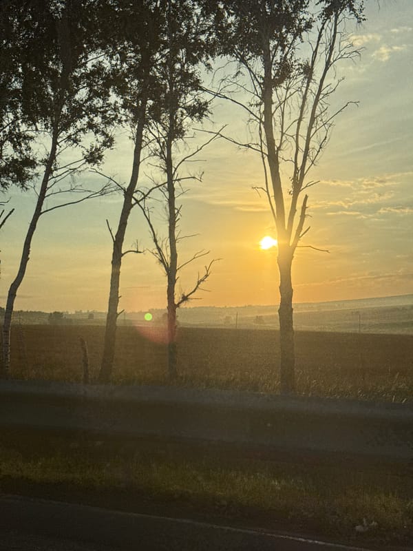 Sunrise breaks over a silhouetted rural landscape in Russia