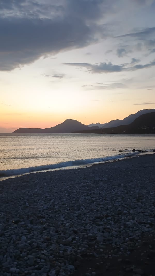 Sunset transforms rocky beach sky from gray to orange
